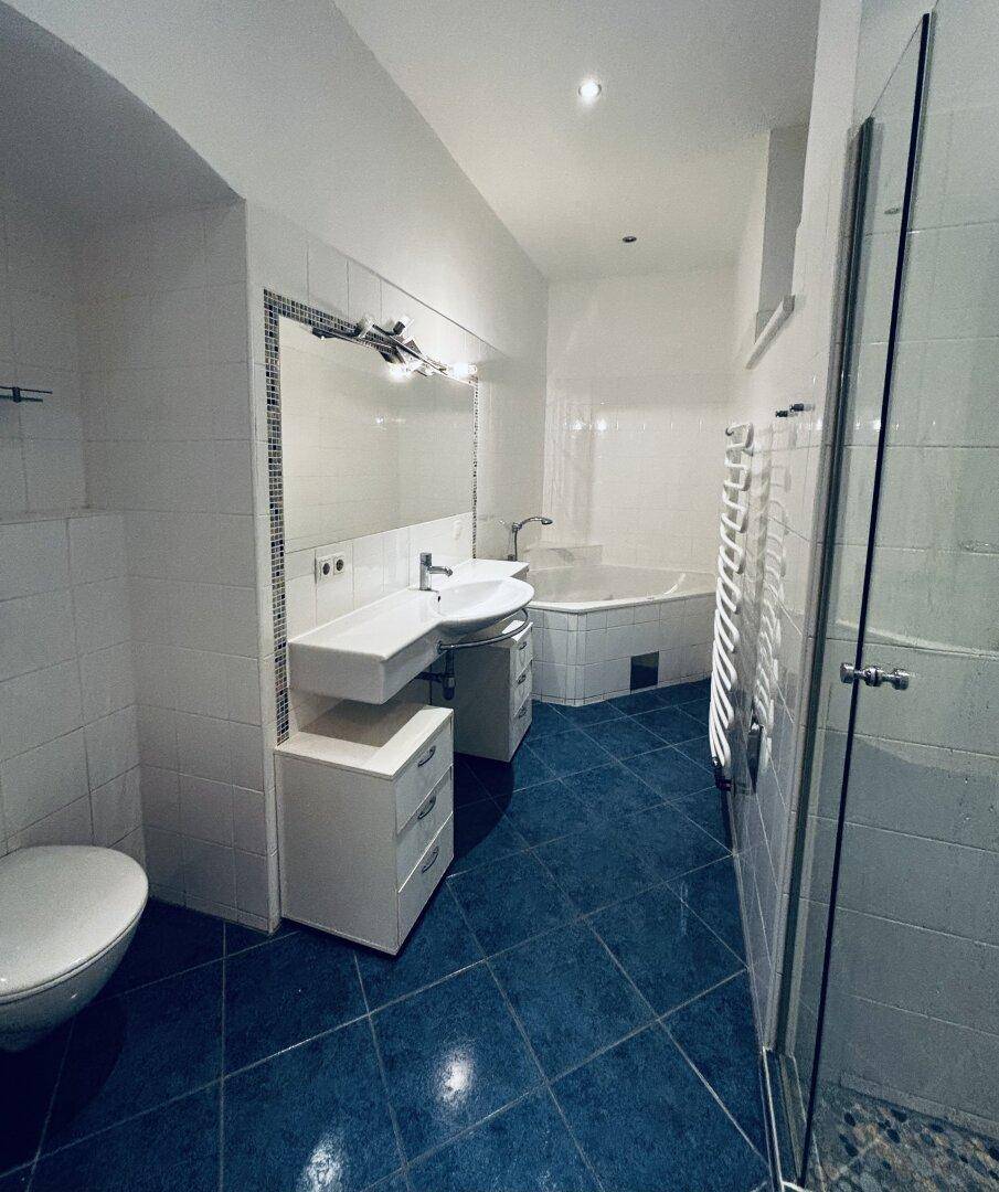 Modernes Badezimmer mit blauen Fliesen, Eckbadewanne, separater Dusche und Doppelwaschbecken.