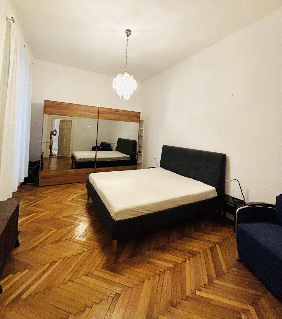 Geräumiges Schlafzimmer mit Fischgrätparkett, Doppelbett und großem Spiegelschrank für viel Stauraum.