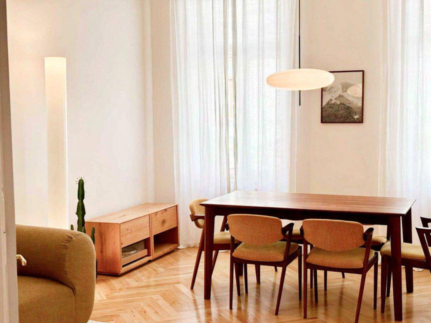 Eleganter Essbereich mit Holztisch, modernen Stühlen und hellem Fischgrätparkettboden.