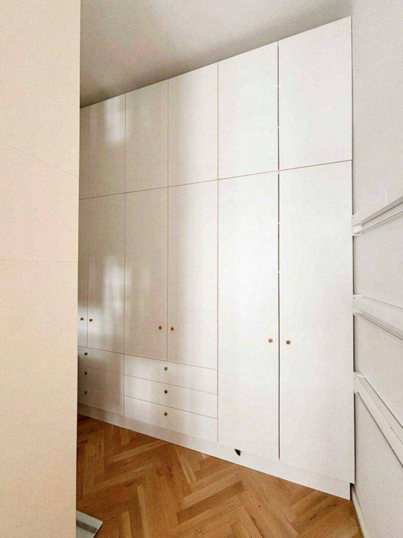 Großer Einbauschrank mit viel Stauraum im hellen Flur mit Fischgrätparkettboden.