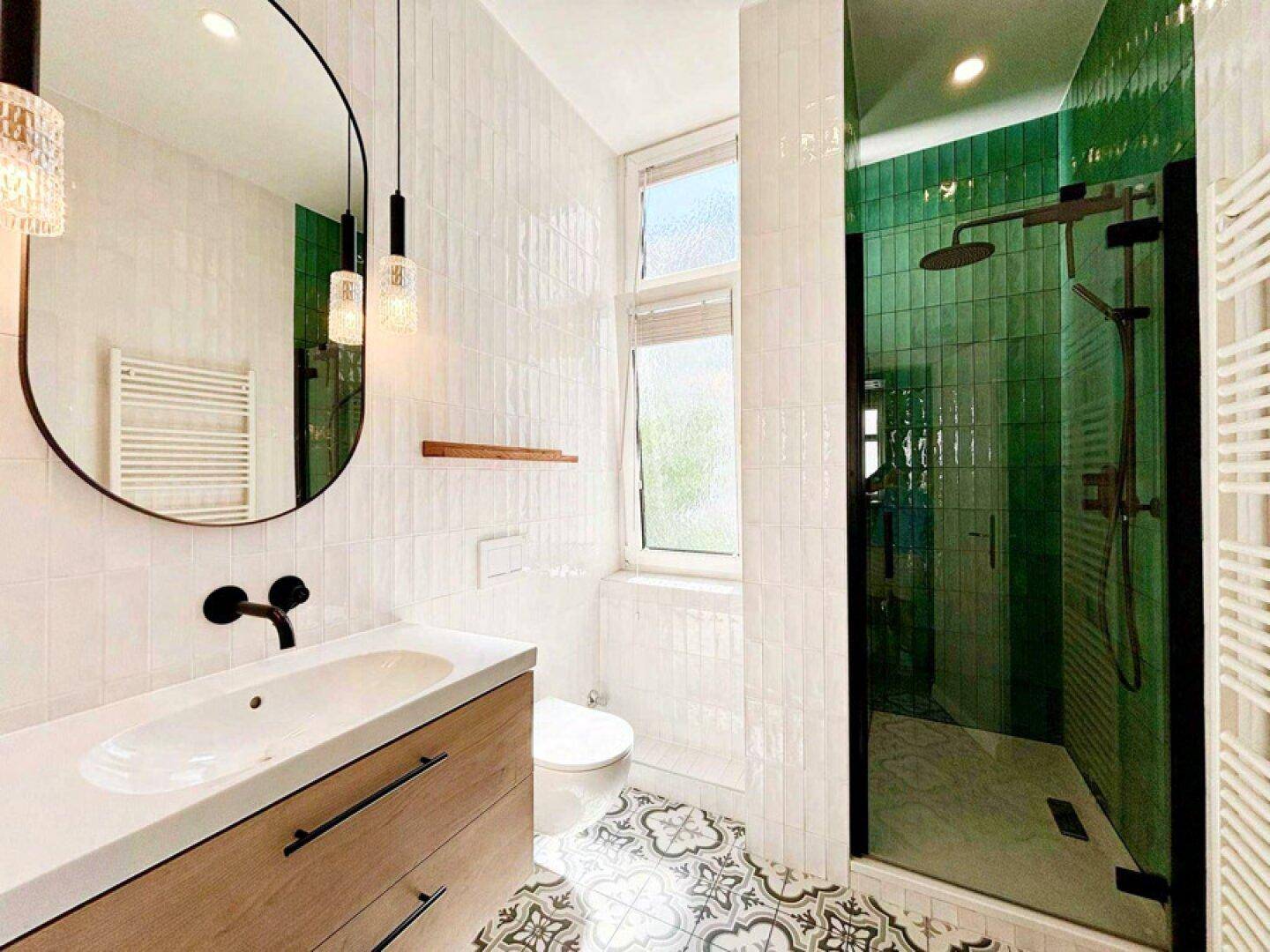 Modernes Badezimmer mit grünen Fliesen, begehbarer Dusche und stilvollem Waschbecken mit Holzunterschrank.