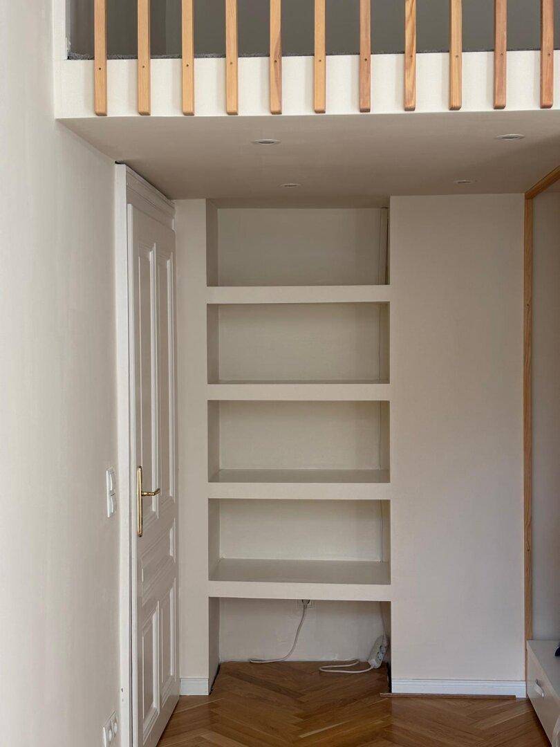 Integrierte Regale unter der Galerie im Arbeitszimmer mit Holzboden und hohen Decken.