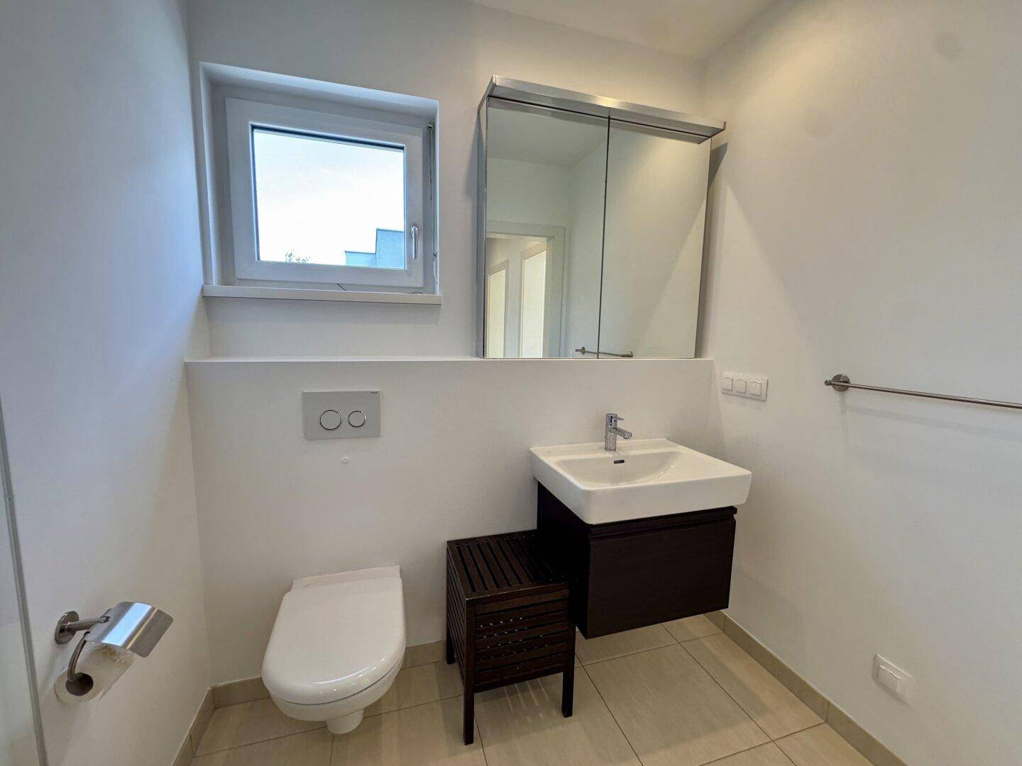Modernes Gäste-WC mit beigen Fliesen, wandhängender Toilette und Spiegelschrank.