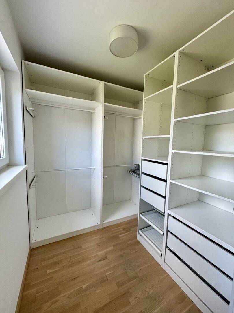 Begehbarer Kleiderschrank mit weißen Regalen und Schubladen für viel Stauraum.