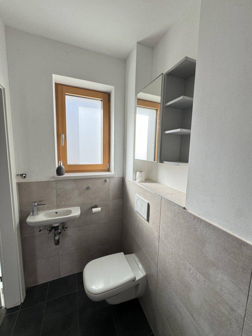 Kleines Gäste-WC mit Fenster, Wand-WC und Handwaschbecken.