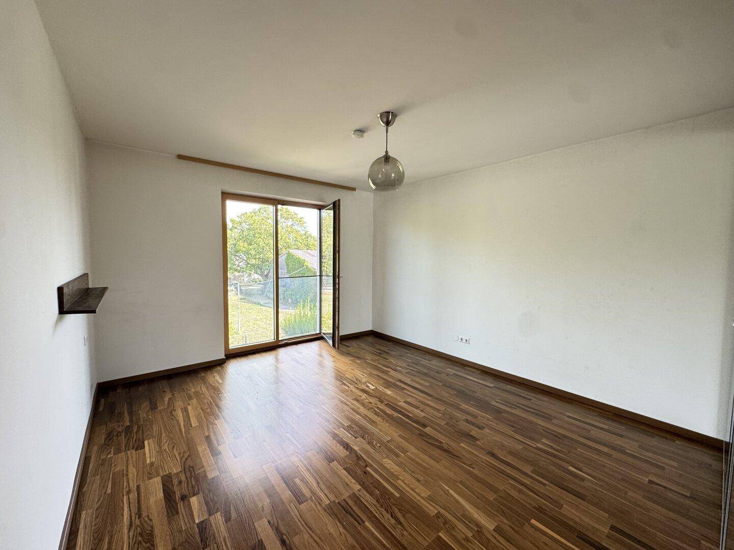 Geräumiges Schlafzimmer mit Parkettboden und Zugang zum Außenbereich.