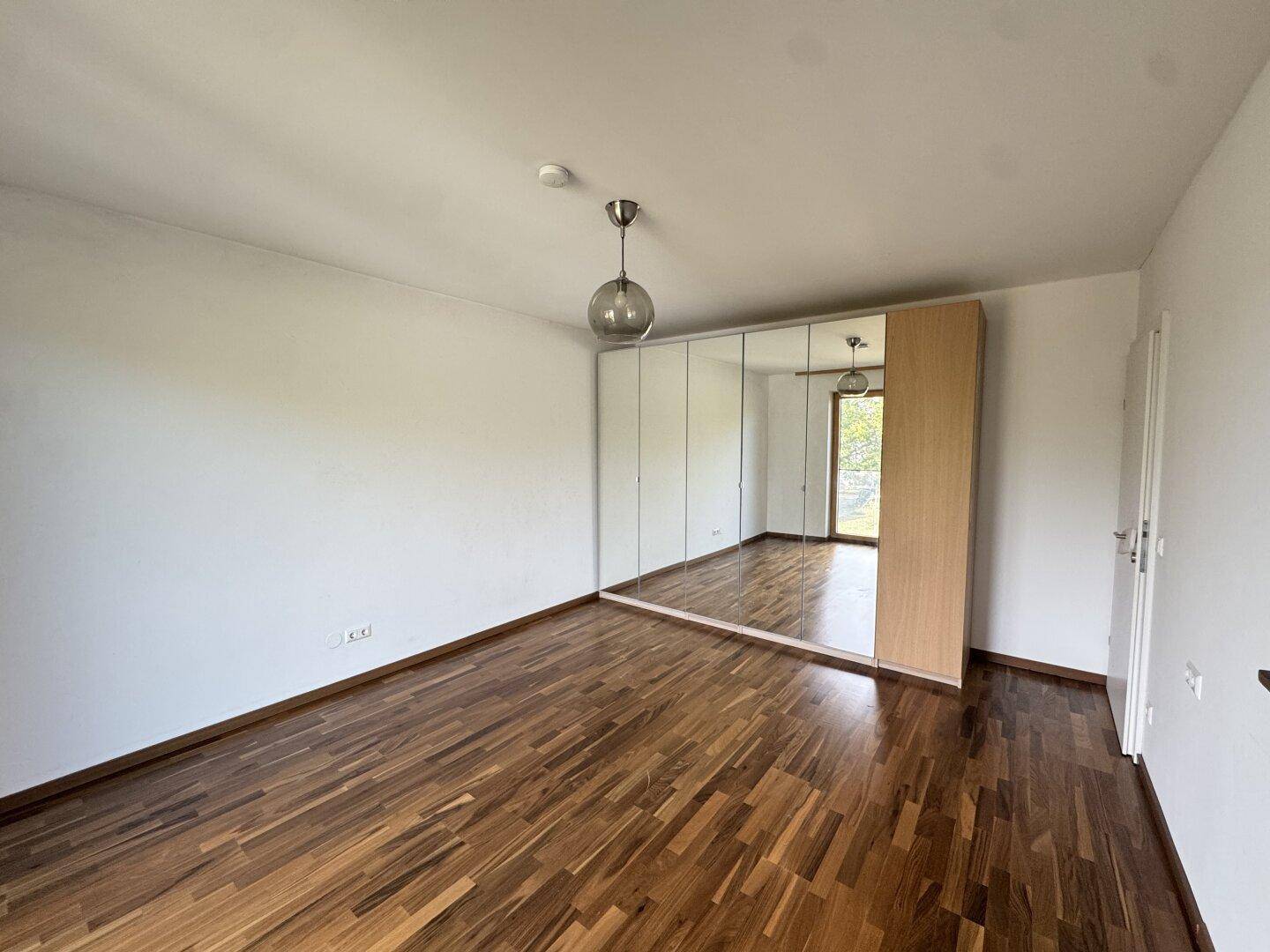 Schlafzimmer mit Parkettboden und großem Spiegelschrank, der den Raum optisch vergrößert.