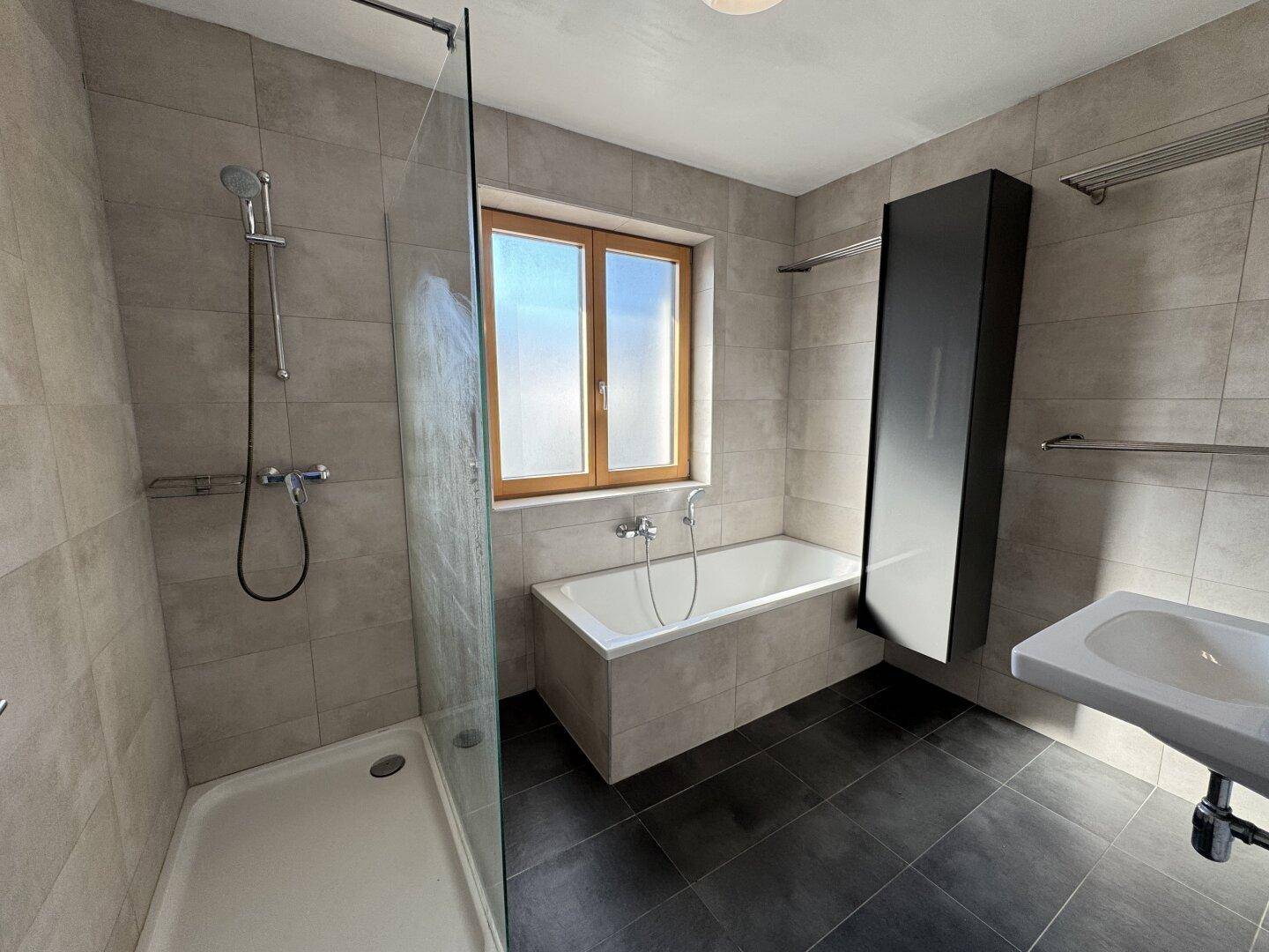 Modernes Badezimmer mit Dusche, Badewanne, Waschbecken und Fenster.