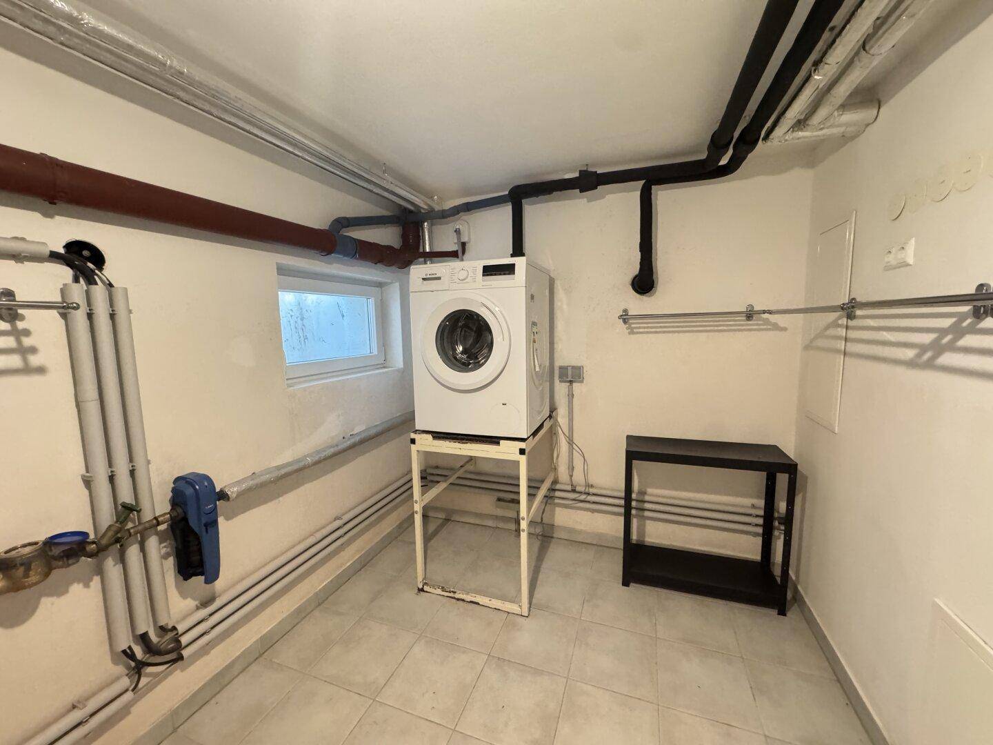 Praktischer Hauswirtschaftsraum im Keller mit Waschmaschine und Installationen.