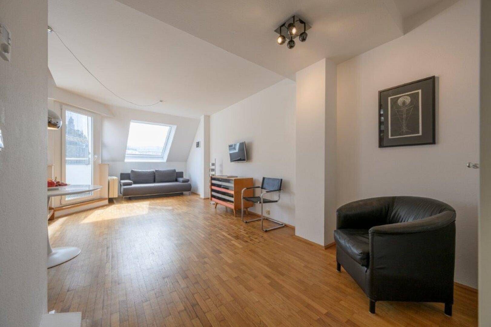 Wohnzimmer mit Parkettboden, Ledersessel und Dachfenstern.