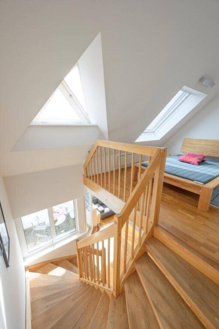 Holztreppe führt zum oberen Schlafbereich mit Dachfenstern.