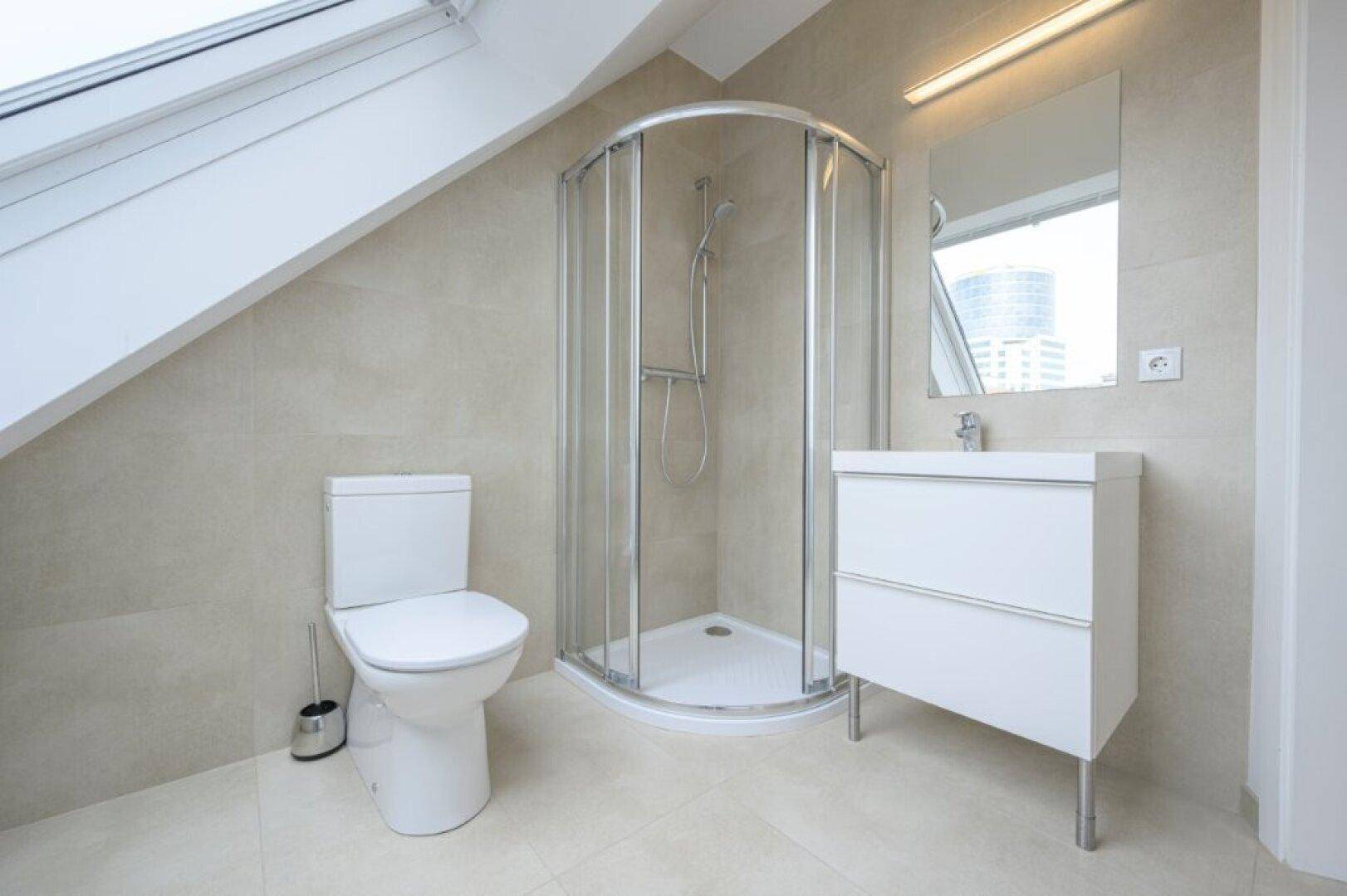 Modernes Badezimmer im Dachgeschoss mit Dusche, WC und Waschtisch.