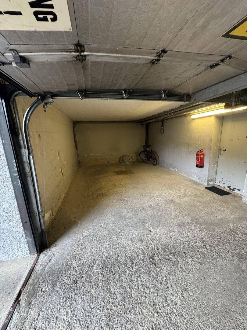 Geräumige Tiefgarage mit Betonboden und Rolltor, ideal für Fahrzeug und Lagerung.