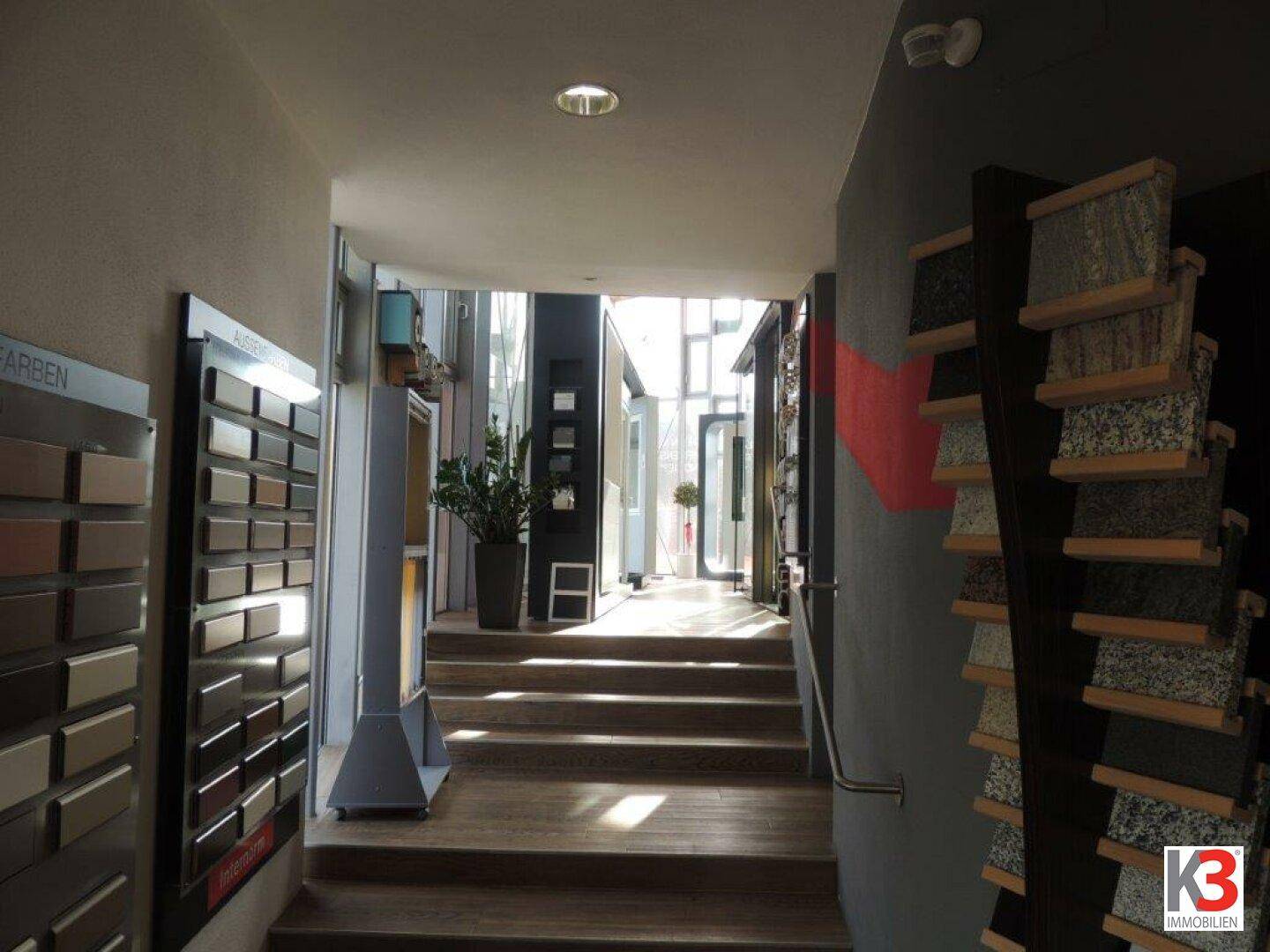 Heller Treppenaufgang mit Musterausstellungen für Materialien und viel Tageslicht von oben.
