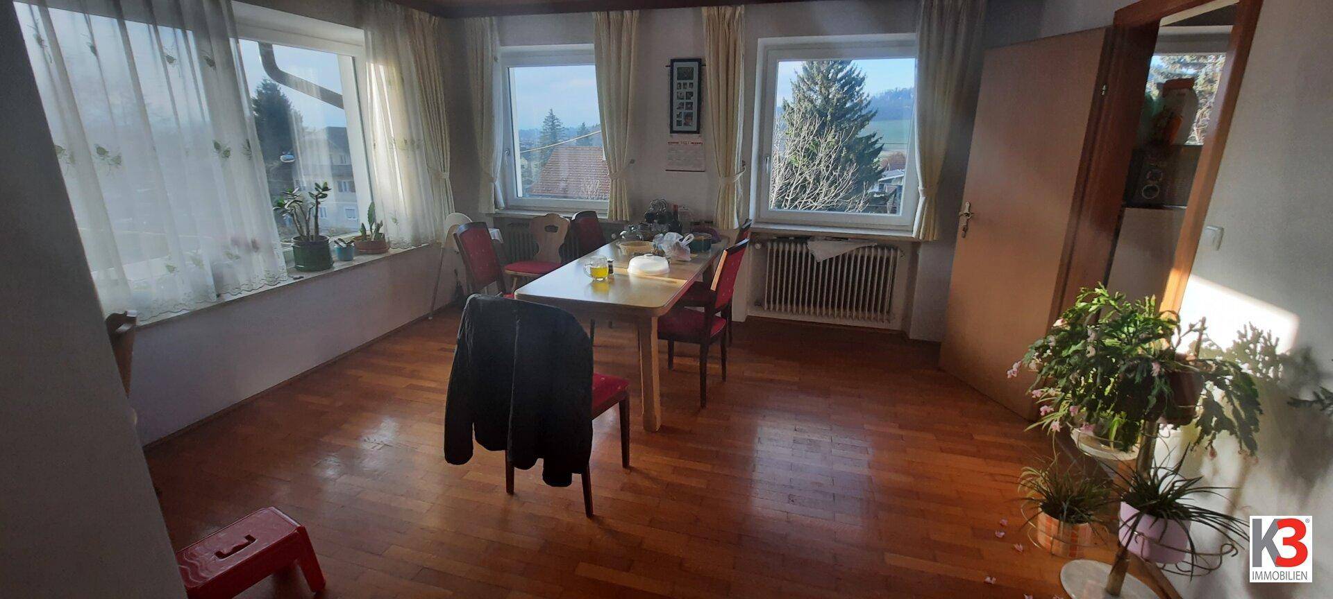 Heller Essbereich mit Holzboden, großen Fenstern und Blick auf die umliegende Landschaft.