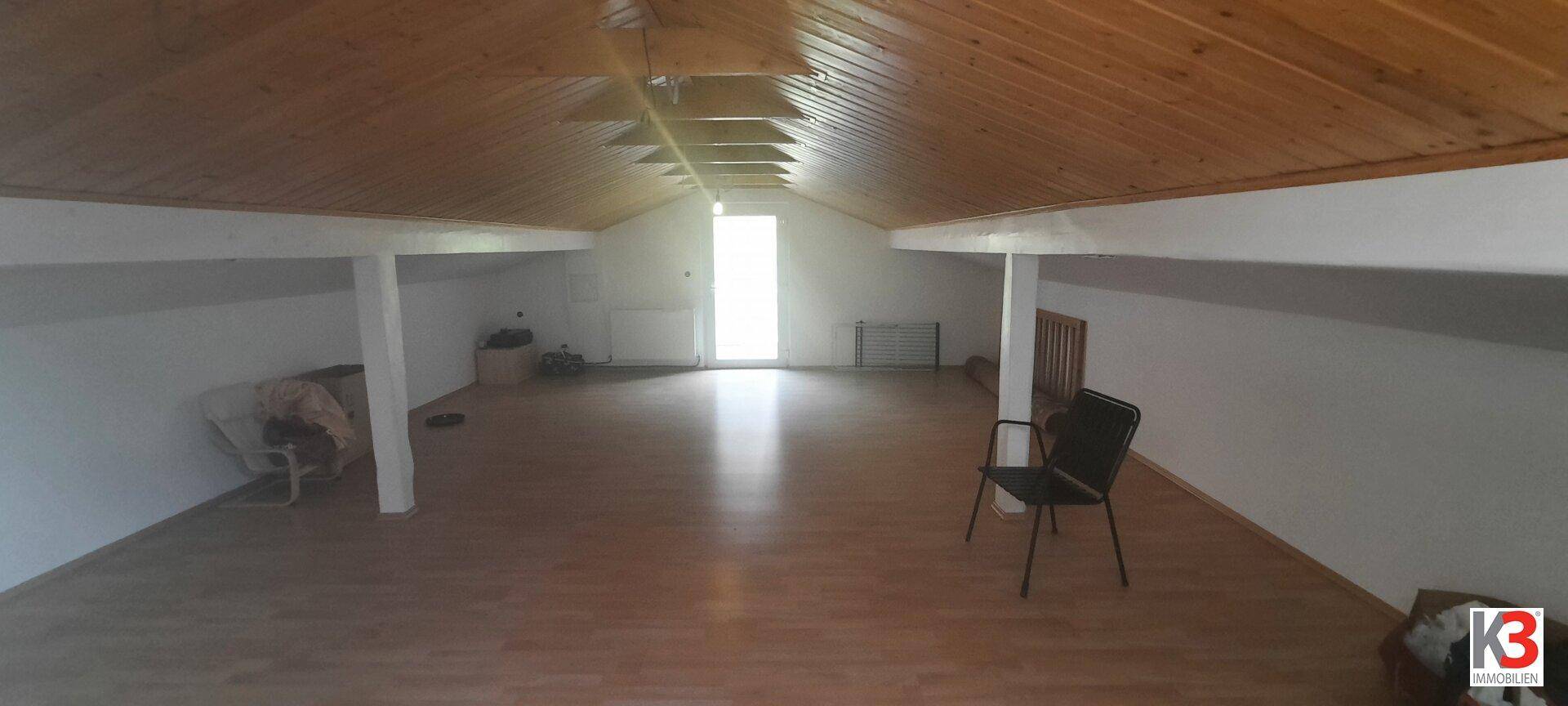 Ausgebauter Dachboden mit Holzverkleidung an der Decke und Laminatboden, bietet viel Raum.
