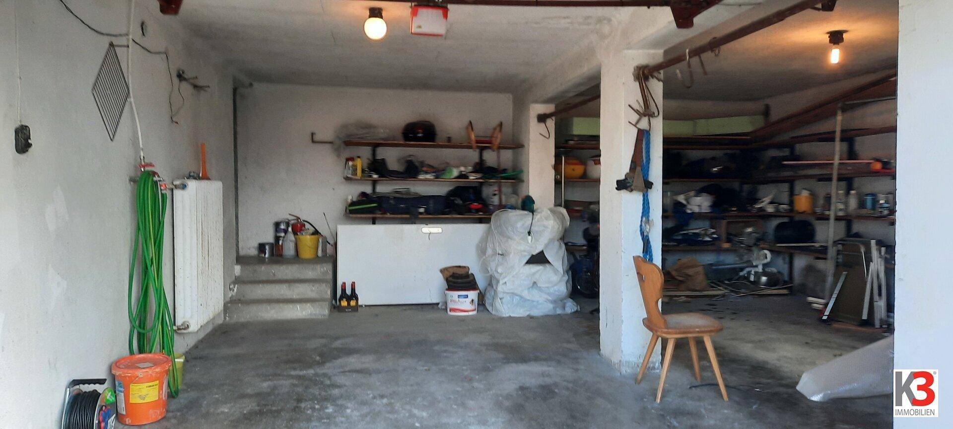 Geräumige Garage mit Betonboden und Regalen für Lagerung und Werkzeuge.