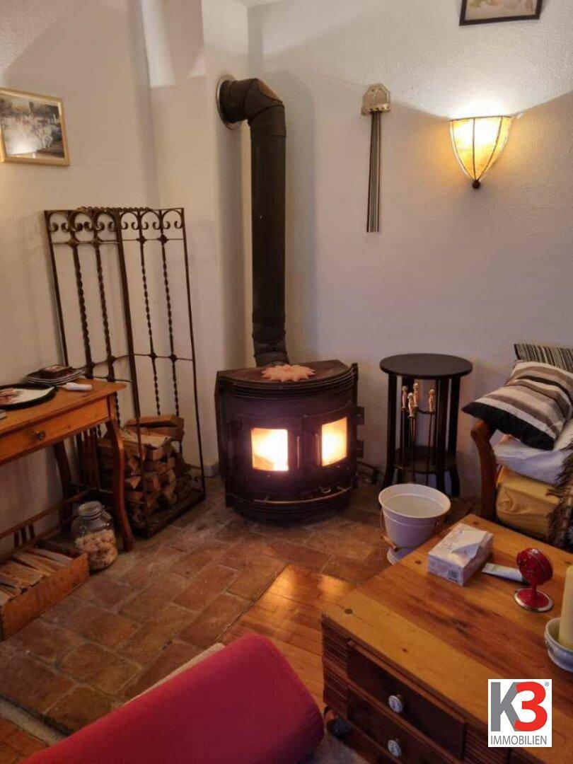 Gemütliche Wohnecke mit einem funktionierenden Holzofen und rustikalen Fliesenboden.