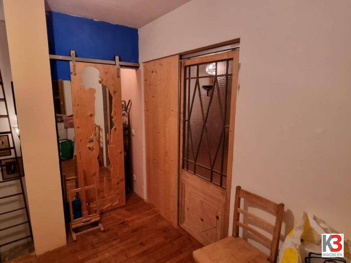 Flur mit rustikaler Schiebetür aus Holz und einer weiteren Holztür mit Bleiglasfenster.