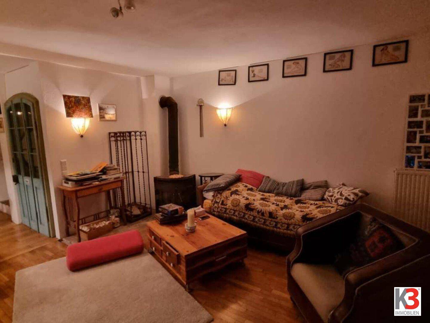 Wohnzimmer mit Holzofen, bequemer Couch und warmem Holzfußboden, ideal für entspannte Abende.