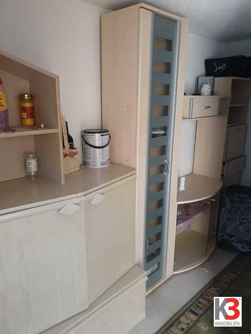 Detailansicht eines hellen Schranks mit Glasfront und Ablageflächen.