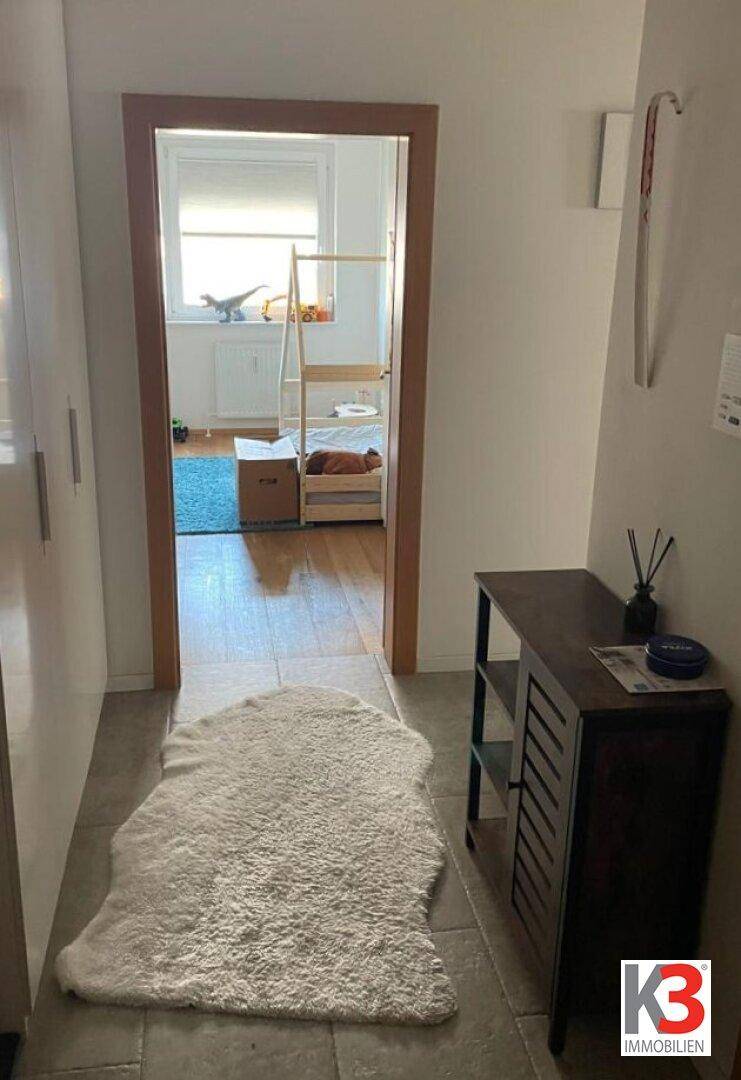 Heller Flur mit Fliesenboden und Blick in ein Kinderzimmer.
