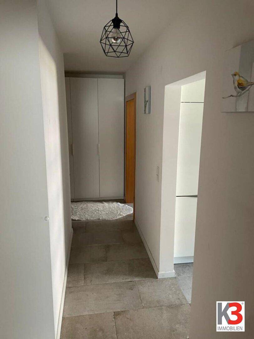 Langer Flur mit Fliesenboden und Blick auf einen Kleiderschrank.