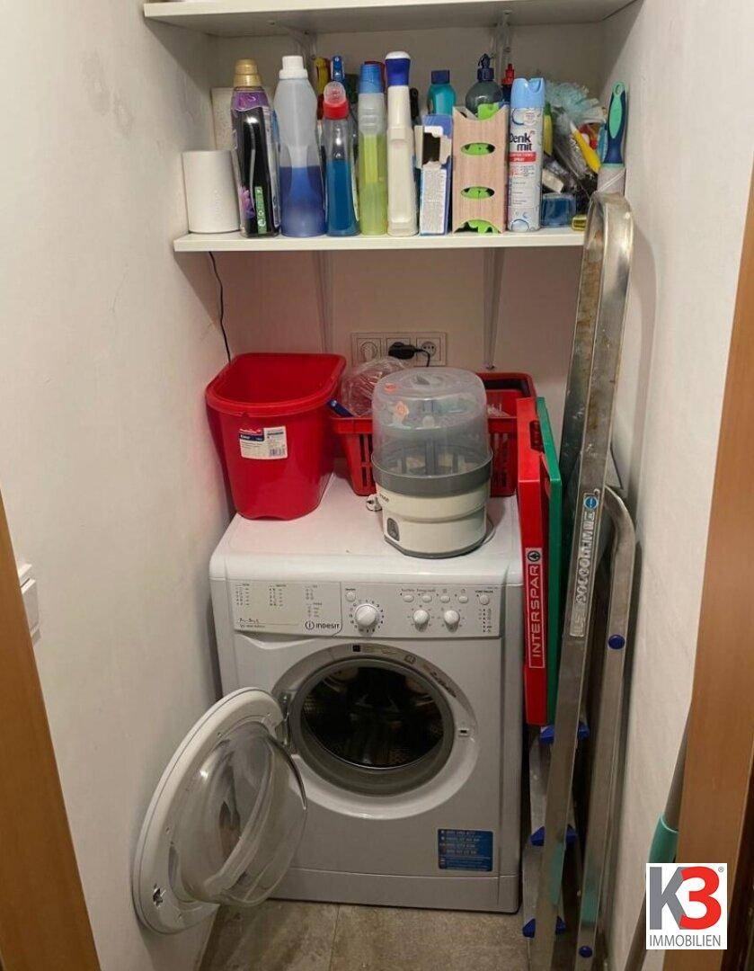 Praktischer Hauswirtschaftsraum mit Waschmaschine und Stauraum für Reinigungsutensilien.