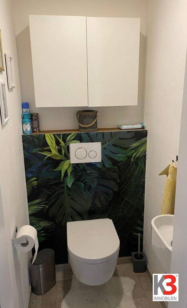 Gäste-WC mit Wand-WC, kleinem Waschbecken und dekorativer Tapete.