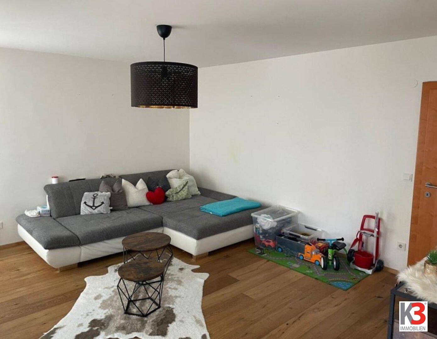 Gemütliches Wohnzimmer mit großem Ecksofa, Holzboden und einem Teppich.