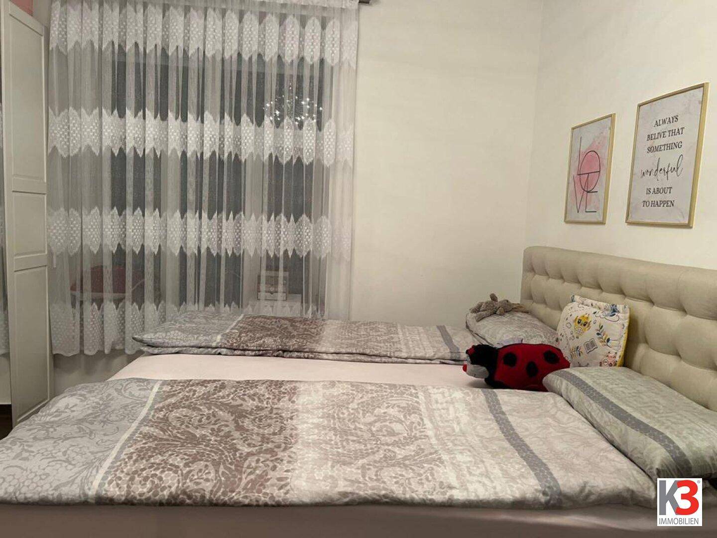 Gemütliches Schlafzimmer mit Doppelbett, Vorhängen und inspirierenden Wandbildern.