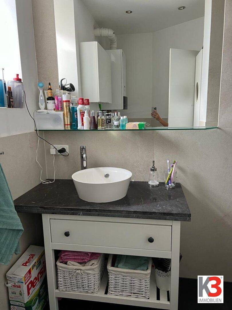 Badezimmer mit modernem Aufsatzwaschbecken, Spiegel und Ablageflächen.