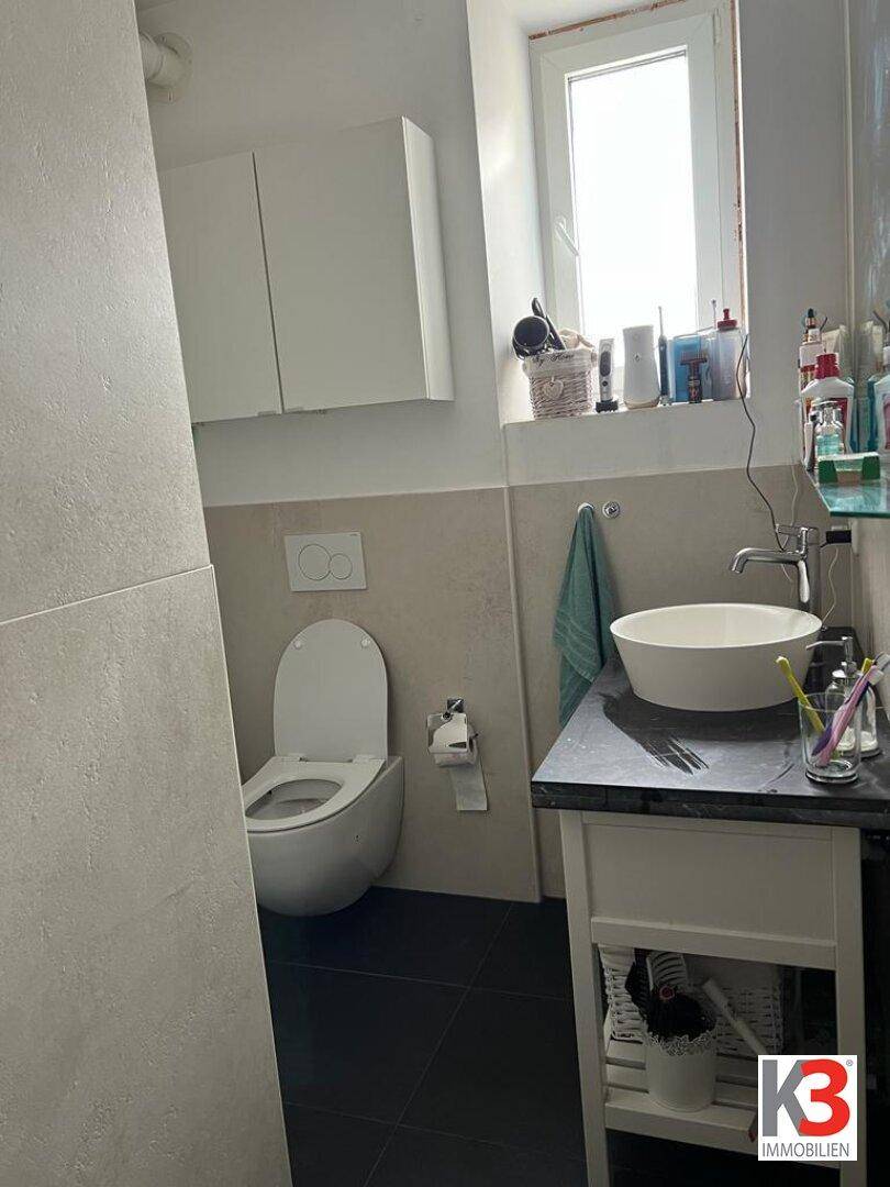 Badezimmer mit Toilette, Aufsatzwaschbecken und Fenster für Tageslicht.