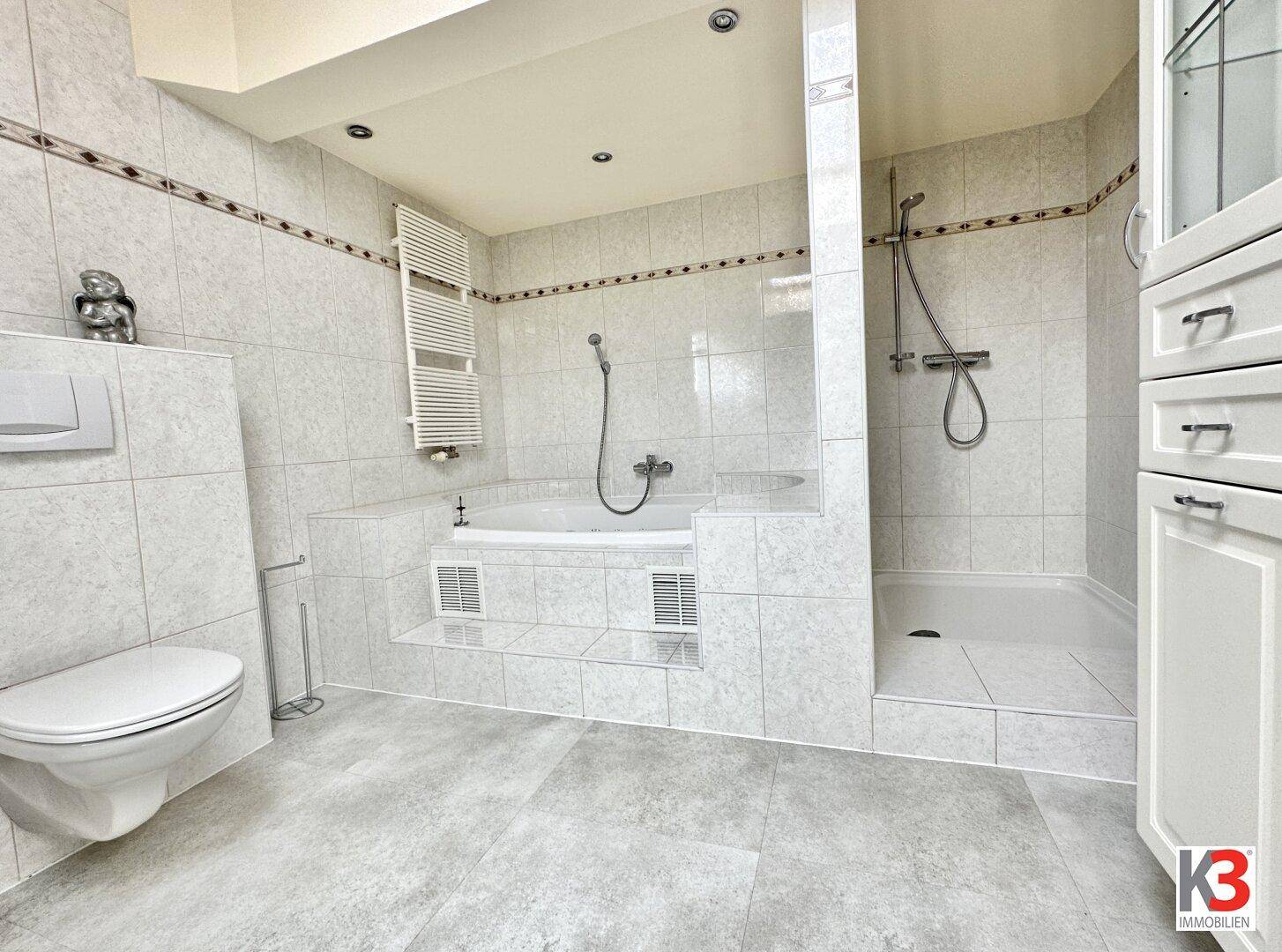 Geräumiges Badezimmer mit Badewanne, Dusche, WC und beheiztem Handtuchhalter.