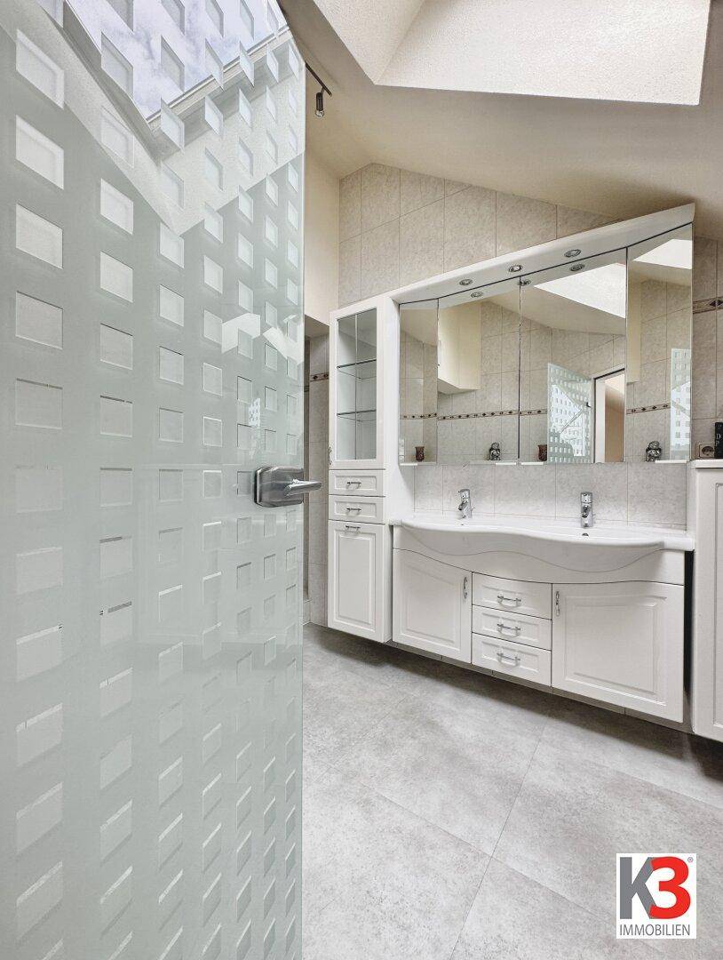 Modernes Badezimmer mit Doppelwaschbecken, Spiegelschrank und hellen Fliesen.