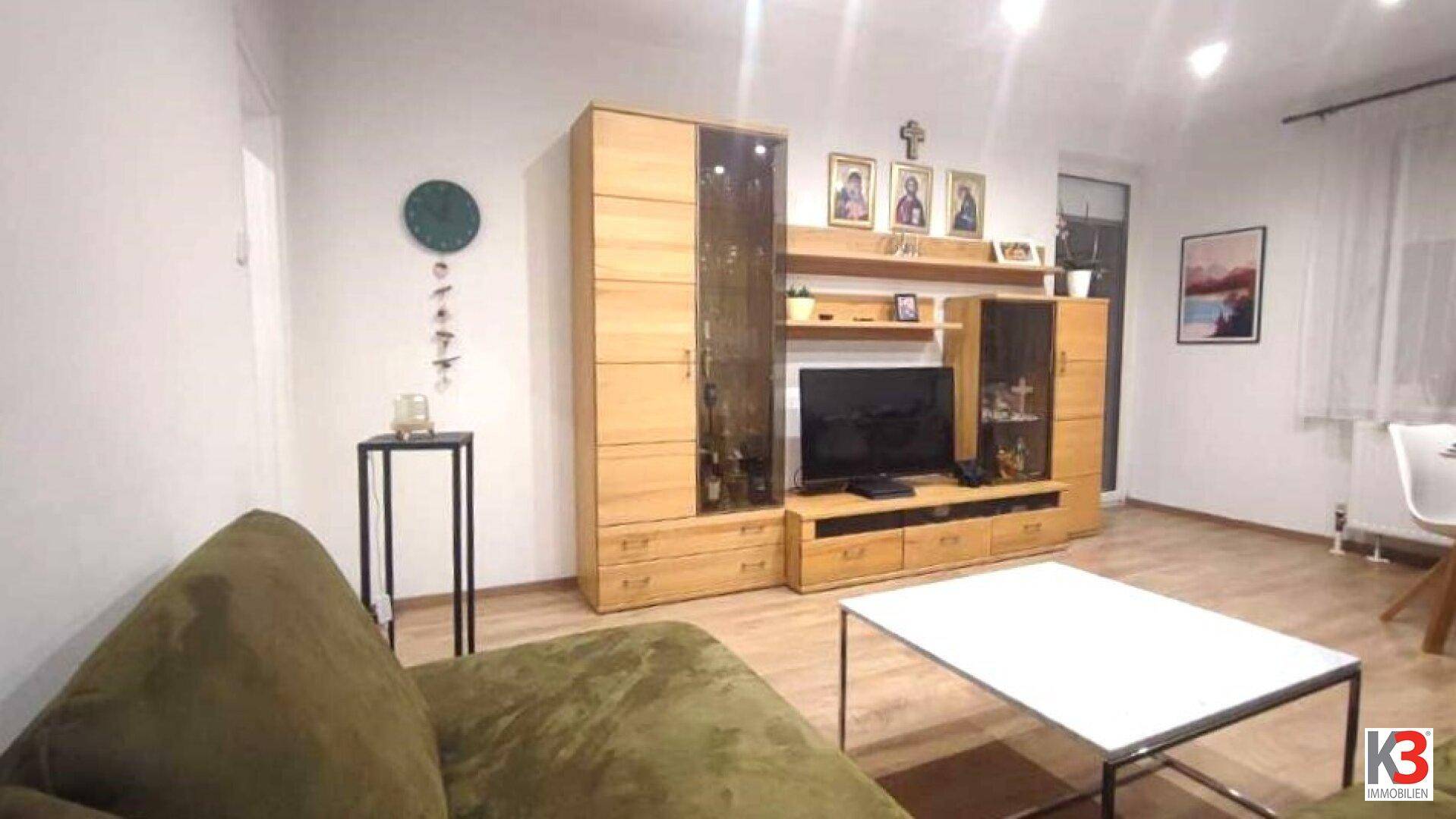 Wohnzimmer mit bequemer Couch, Holzmöbeln und moderner Dekoration.