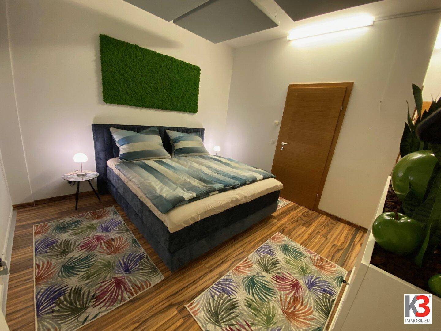 Gemütliches Schlafzimmer mit Doppelbett, Holzboden und einer dekorativen Mooswand als Akzent.