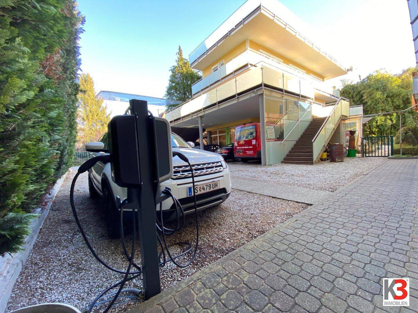 Elektrofahrzeug wird an einer Ladestation vor dem Gebäude auf dem Parkplatz geladen.