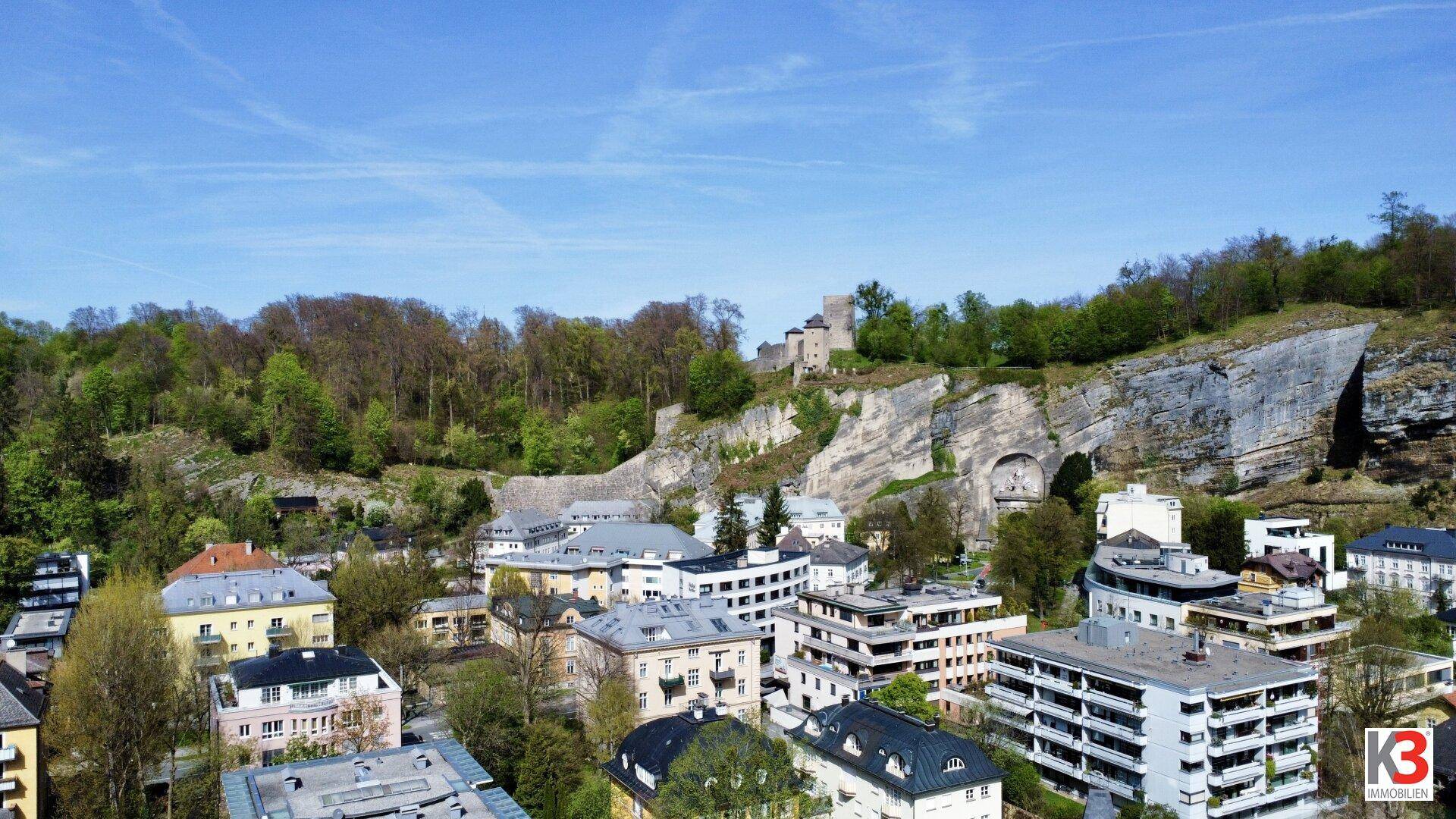 Luftaufnahme einer Stadt mit Felsformationen, historischen Gebäuden und einer Burg auf dem Hügel.