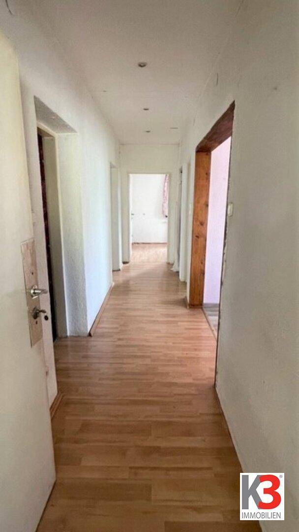 Langer Flur mit Holzboden und mehreren Türen, der zu verschiedenen Räumen führt.
