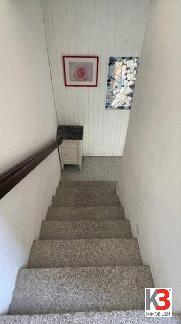 Treppenhaus mit Teppichstufen und Holzgeländer, das in die untere Etage führt.