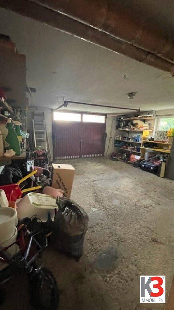 Geräumige Garage mit viel Stauraum und einem großen Garagentor im Hintergrund.