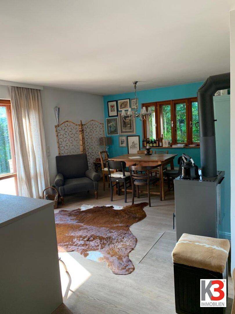 Rustikaler Essbereich mit Holztisch, blau gestrichener Wand und gemütlichem Holzofen.