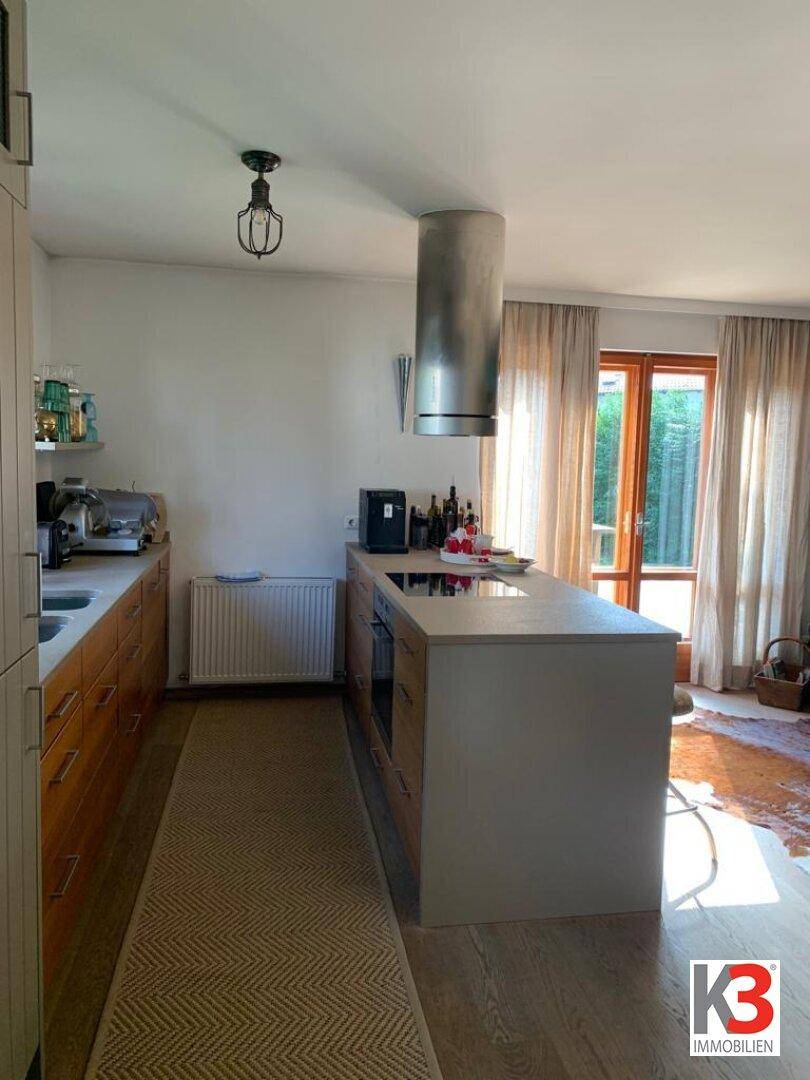 Helle Küche mit Kochinsel, Induktionskochfeld und Zugang zur Terrasse.