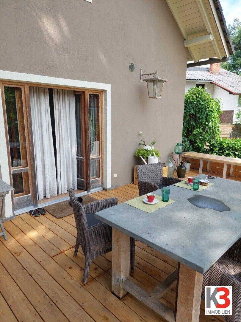 Gemütliche Holzterrasse mit Esstisch und Korbstühlen, direkt am Haus gelegen.