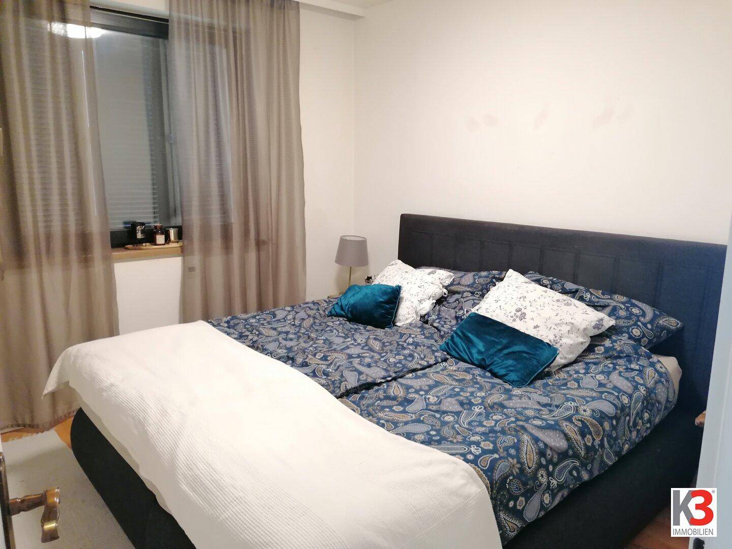 Schlafzimmer mit Doppelbett und grauen Vorhängen für eine ruhige Atmosphäre.