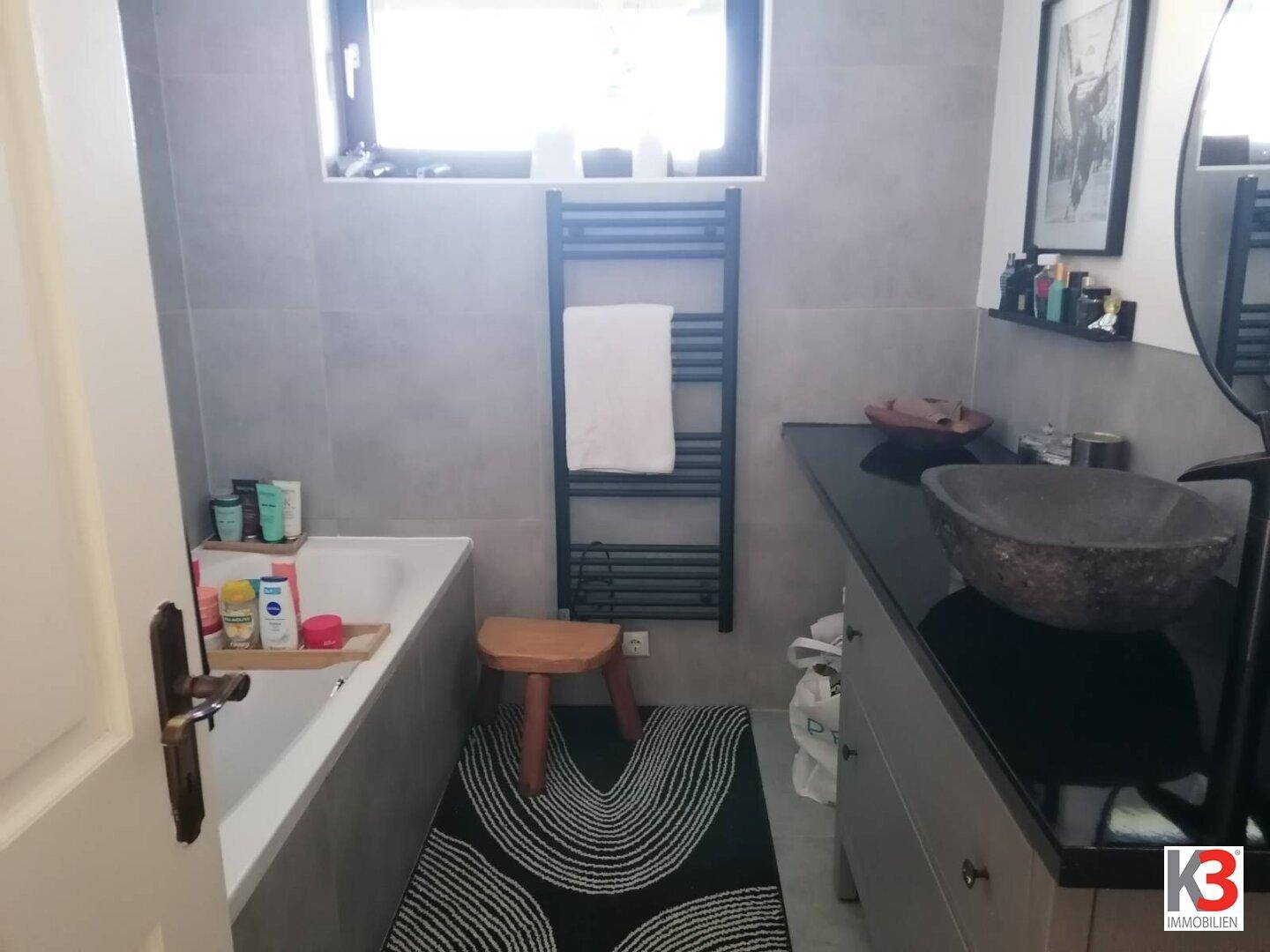 Modernes Badezimmer mit Badewanne, stilvollem Waschbecken und beheiztem Handtuchhalter.