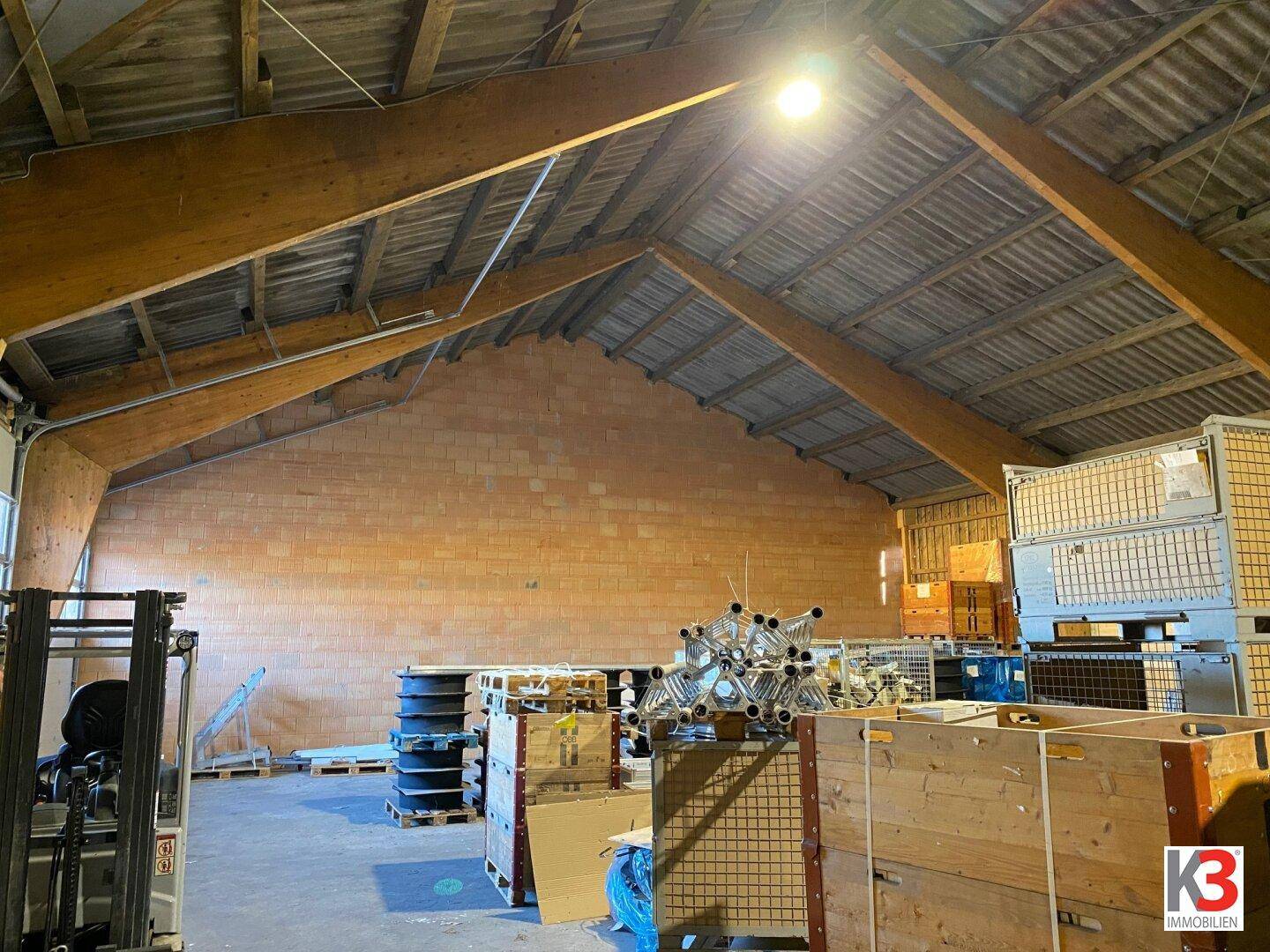 Weitläufige Lagerhalle mit hohen Holzdecken, unverputzten Ziegelwänden und industrieller Ausstattung für vielfältige Lagerzwecke.