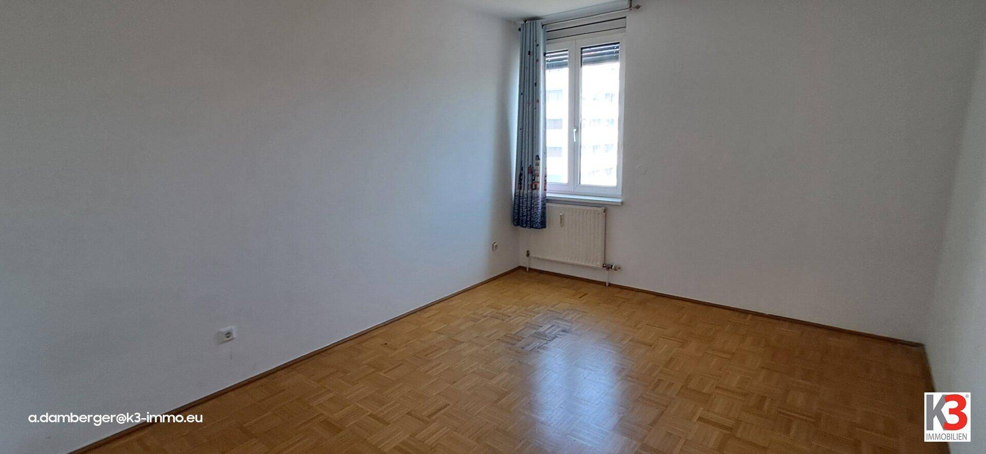 Gemütliches Schlafzimmer mit Parkettboden und einem Fenster, das eine ruhige Atmosphäre schafft.