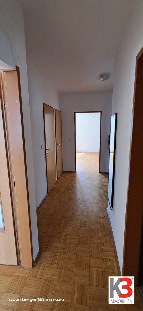 Langer Flur mit Parkettboden und mehreren Türen, der die verschiedenen Bereiche der Wohnung verbindet.